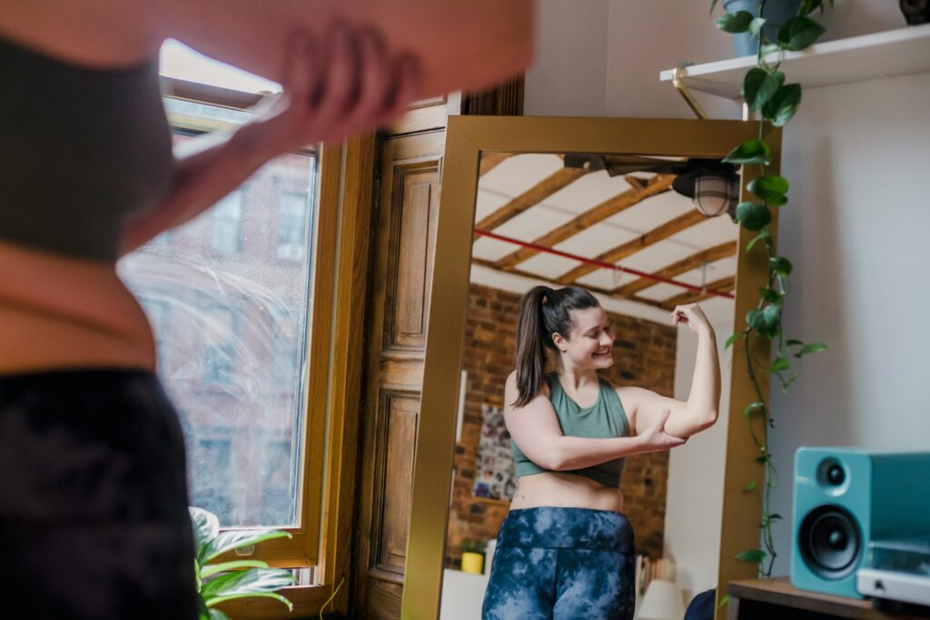 Your body is strong and capable. Woman shows off her muscles in the mirror.